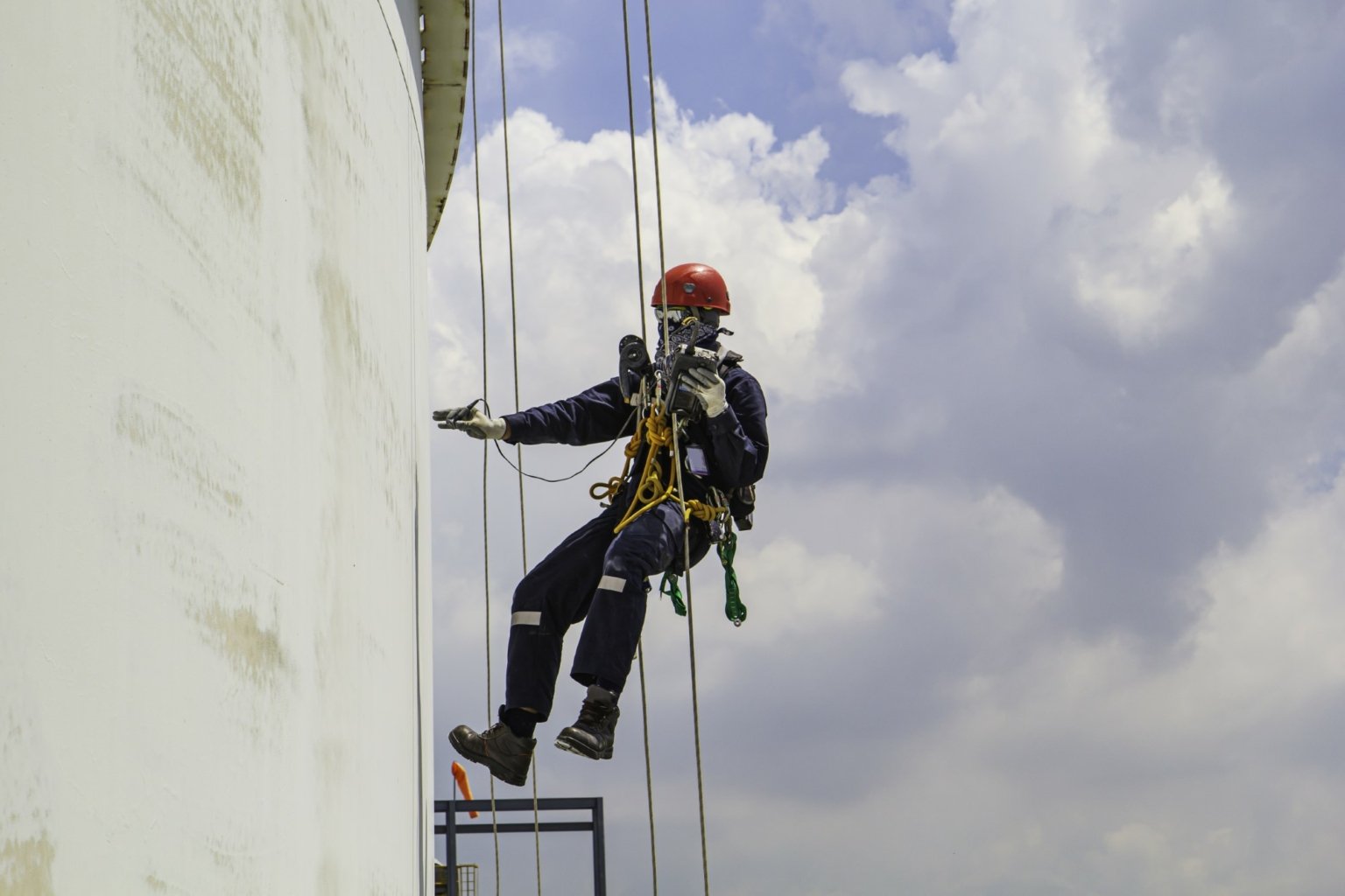 Cordiste FP Est descendant en rappel le long d'une cuve industrielle pour inspection